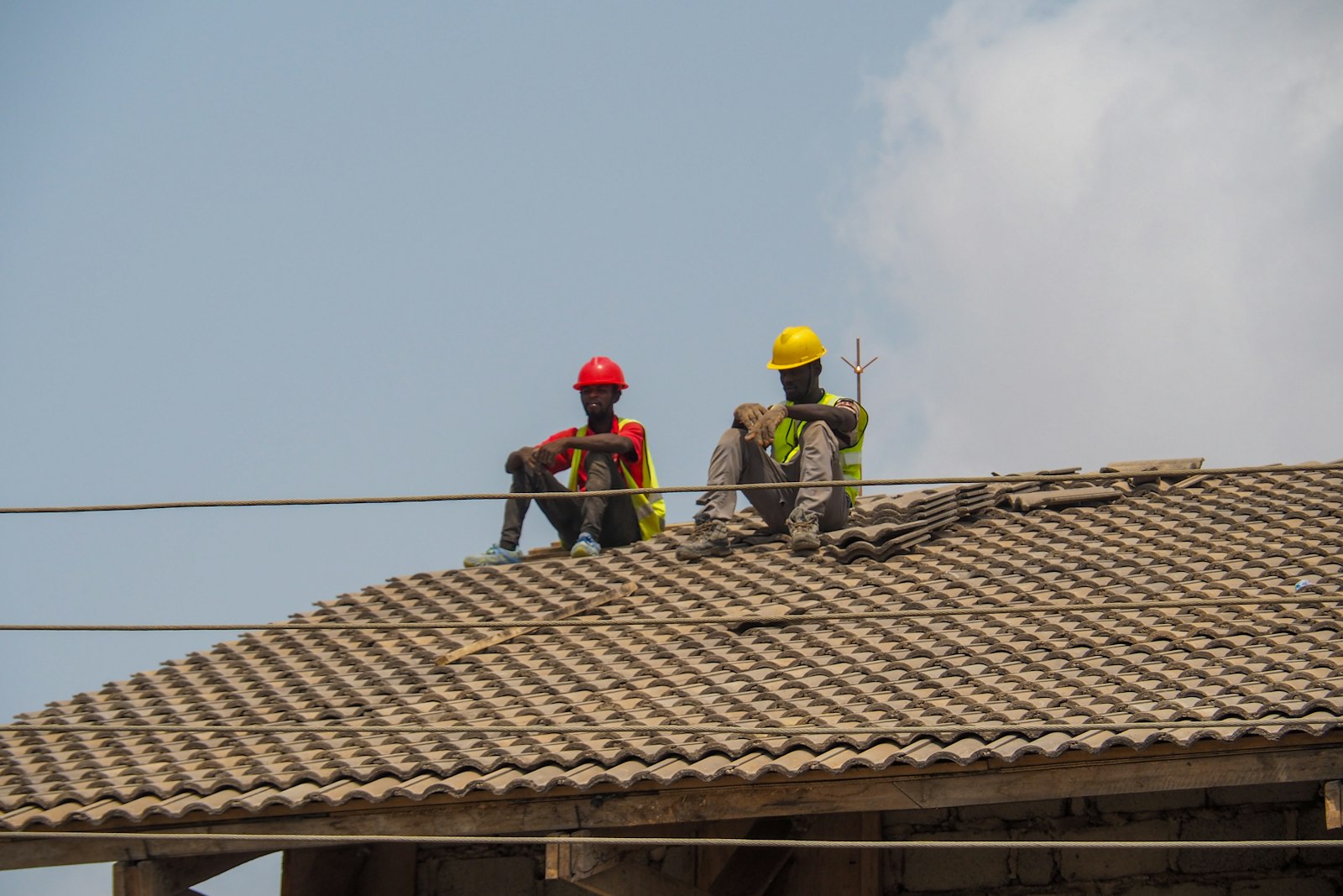 Deux ouvriers en casque sur la toiture d'un bâtiment